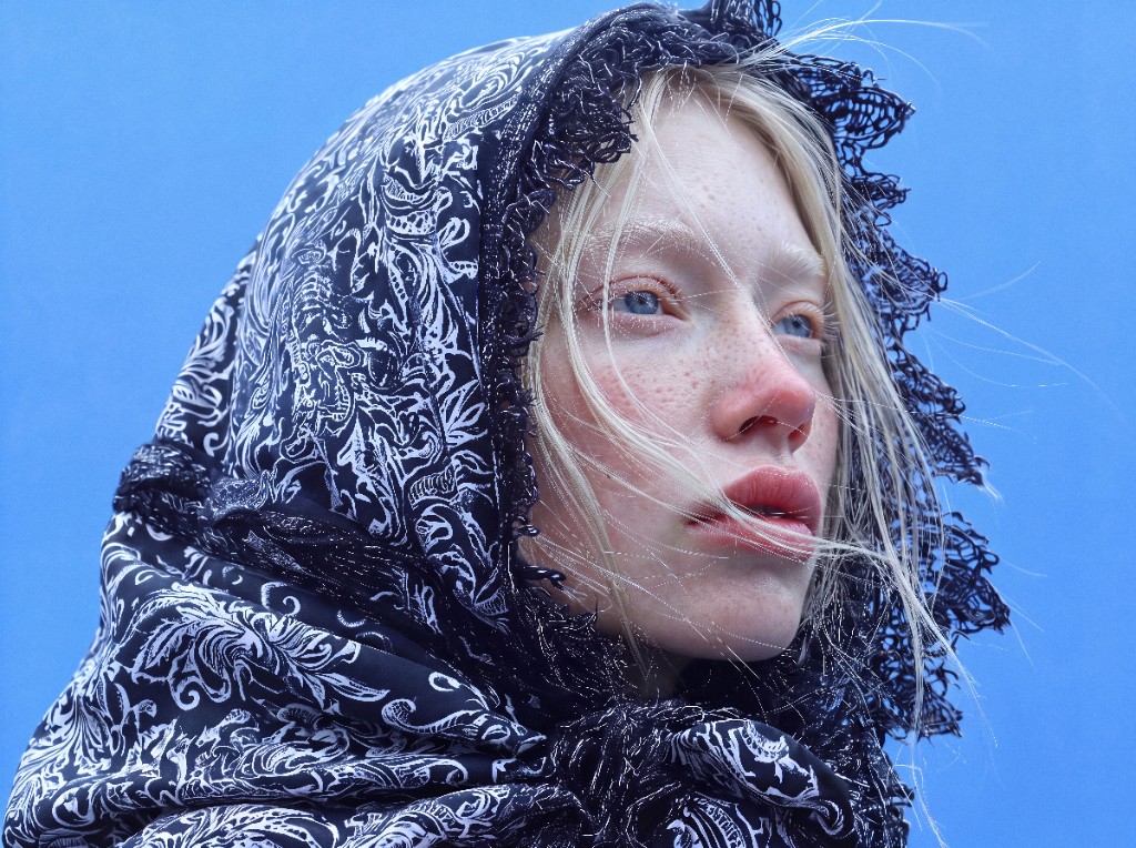 Close-up portrait with a Delft-patterned headscarf against blue