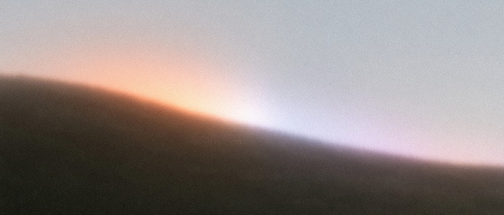 Grainy twilight ridge with a glowing peach and lavender horizon