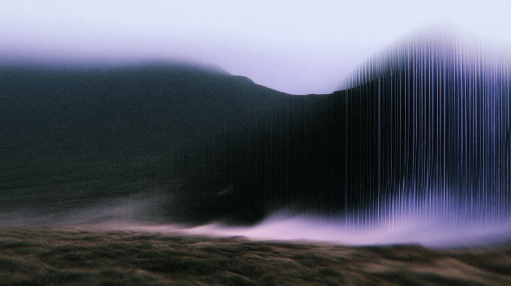 Dark mountain ridge with vertical purple and blue light streaks